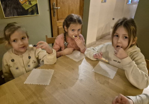 Dziewczynki siedzą przy stoliku i jedzą ciasteczka