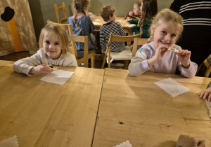 Dziewczynki siedzą przy stoliku i jedzą ciasteczka