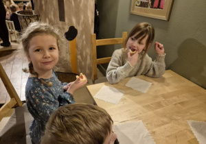 Dziewczynki siedzą przy stoliku i jedzą ciasteczka