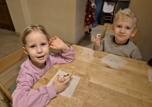 Dzieci siedzą przy stoliku i jedzą ciasteczka