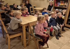 Dzieci siedzą na krzesełkach i czekają na rozpoczęcie przedstawienia