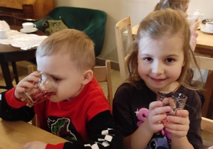 Dzieci przy stolikach piją kompot.