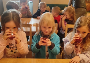 Dziewczynki przy stoliku piją kompot.