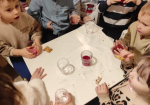 Dzieci przy stoliku piją kompot.