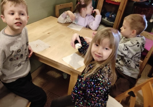 Dzieci przy stoliku jedzą ciasteczka.