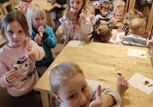 Dziewczynki przy stoliku jedzą ciastka.