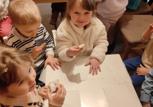 Dzieci jedzą ciasteczka przy stoliku.