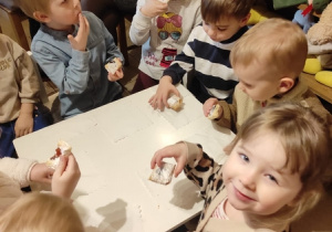 Dzieci jedzą ciastka przy stoliku.