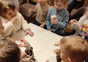 Dzieci jedzą ciasteczka przy stoliku.