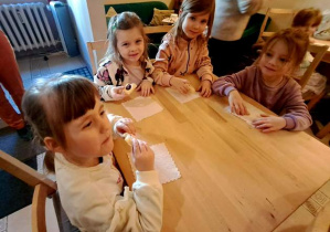 Dziewczynki siedzą przy stoliku i jedzą słodki poczęstunek