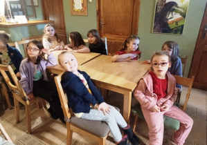 Dzieci siedzą przy stołach w oczekiwaniu na spektakl