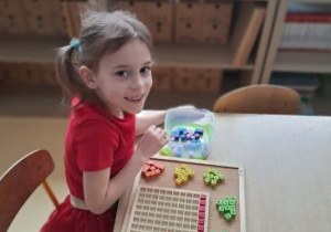 Dziewczynka pozuje do zdjęcia podczas pracy z materiałem rozwojowym