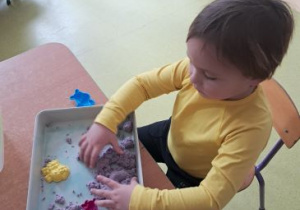 Chłopiec eksperymentuje z piaskiem kinetycznym