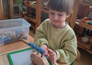 Chłopiec z uśmiechem konstruuje swój samochód