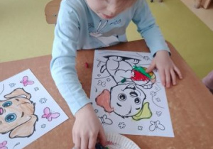 Dziewczynka koloruje pastelami ilustrację psa