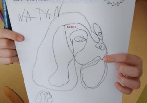 Dziecko prezentuje swoją pracę przedstawiającą psa
