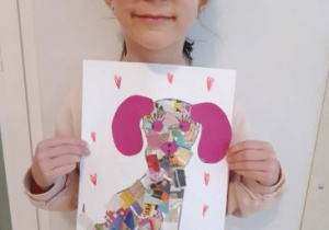 Dziewczynka pozuje do zdjęcia ze swoją pracą plastyczną