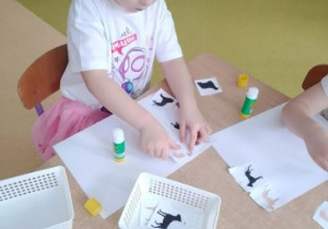 Dziewczynka przykleja wycięte elementy