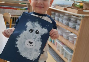 Chłopiec pozuje do zdjęcia ze swoją pracą przedstawiającą niedźwiedzia polarnego