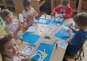 Dzieci siedzą przy stoliku podczas wykonywania działań plastycznych