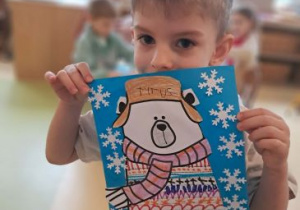 Chłopiec prezentuje swoją pracę plastyczną