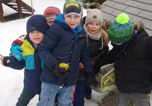 Grupa dzieci pozuje do zdjęcia podczas zimowych zabaw w ogrodzie przedszkolnym