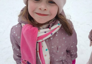 Dziewczynka pozuje do zdjęcia w zimowej aurze podczas zabaw w ogrodzie przedszkolnym