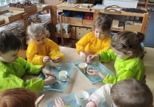 Dzieci łączą ziarna za pomocą smalca przygotowując "pączki dla ptaków"