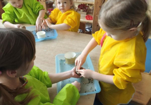 Dzieci łączą ziarna za pomocą smalca przygotowując "pączki dla ptaków"