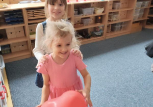 Dziewczyni podczas zabawy tanecznej z czerwonymi balonami w kształcie serduszek