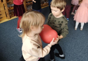 Dzieci podczas zabawy tanecznej z czerwonymi balonami w kształcie serduszek