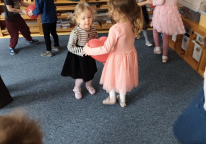 Dzieci podczas zabawy tanecznej z czerwonymi balonami w kształcie serduszek