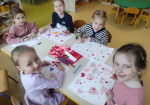 Dziewczynki rysują serca przedstawiające różne emocje.
