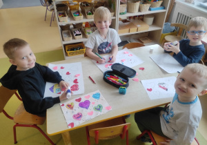 Chłopcy malują kolorowe serca.