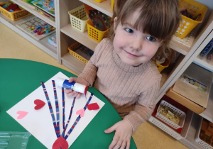 Dziewczynka nakleja walentynkowe serduszka.