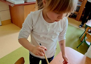 Zosia w czasie zabawy badawczej maluje śnieg farbami