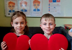 Chłopiec i dziewczynka pozują do zdjęcia z czerwonymi sercami