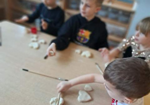 Dzieci przy stoliku ugniatają masę solną