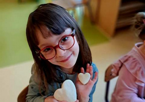 Dziewczynka pozuje do zdjęcia z serduszkami uformowanymi z masy solnej