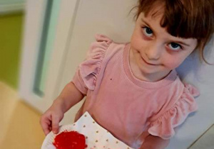 Dziewczynka prezentuje talerz z sercami walentynkowymi zrobionymi z masy solnej podczas warsztatu sensorycznego