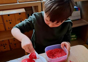 Chłopiec posypuje serca uformowane z masy solnej solą morską w kolorze czerwonym