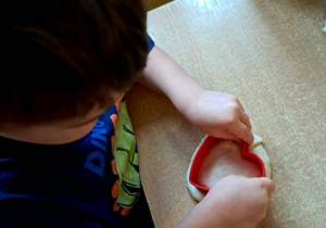 Chłopiec podczas działań manualnych wciska foremkę serca w maskę solną
