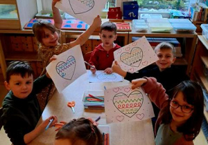 Dzieci przy stoliku podczas działań grafomotorycznych z motywem serca