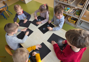 Dzieci kreślą bałwankowe kule w rytm muzyki