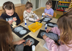 Dzieci naklejają bałwankom oczy i nosy