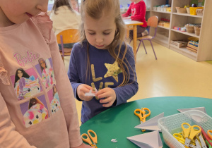 Dziewczynki składają papier, z którego wytną płatki śniegu