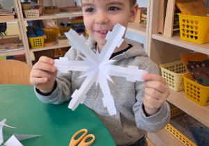 Chłopiec prezentuje wyciętą gwiazdę śniegową