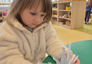 Dziewczynka rozkłada wyciętą śnieżynkę