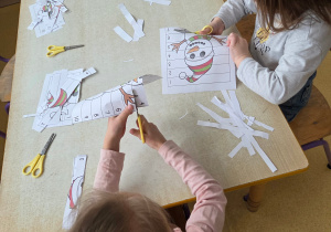 Dzieci wycinają kartę pracy z bałwankiem