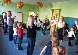 Uczestnicy spotkania stoją w szpalerze i śpiewają piosenkę "Panie Janie"